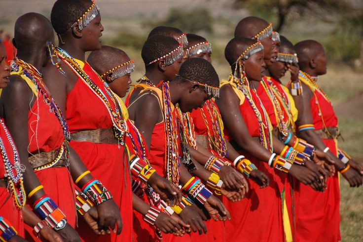 a group of women in red dresses standing next to each other with bracelets on their necks