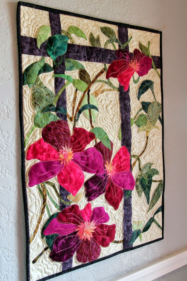 a quilted wall hanging with flowers on it