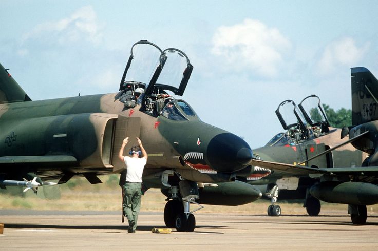 a man standing in front of two fighter jets