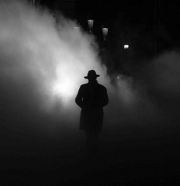 a man standing in the fog with his hat on