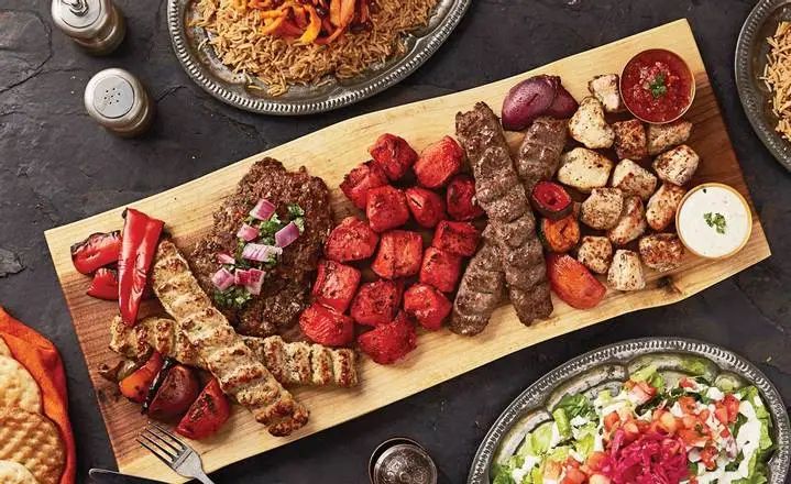 a table topped with different types of meats and veggies on top of plates