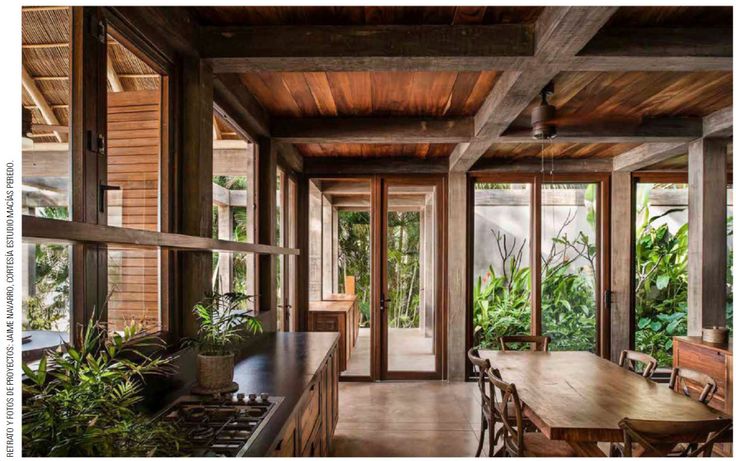 an open kitchen and dining area with wood paneled walls, wooden flooring, and large windows