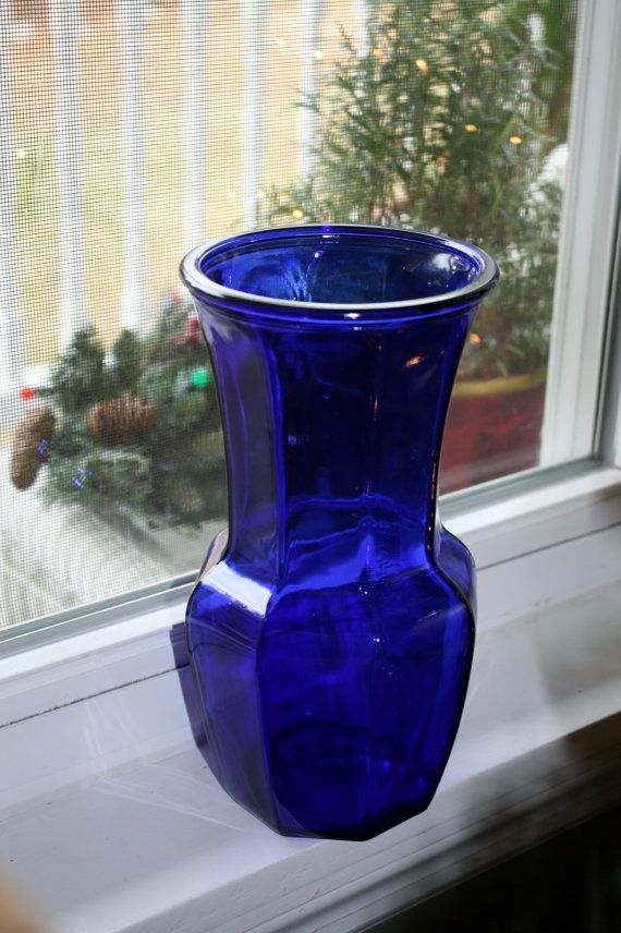 a blue vase sitting on top of a window sill next to a christmas tree