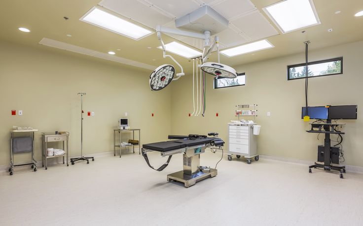 a hospital room with medical equipment and monitors on the wall, including an operating table