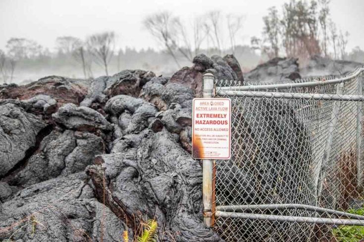 a sign on a fence near some rocks