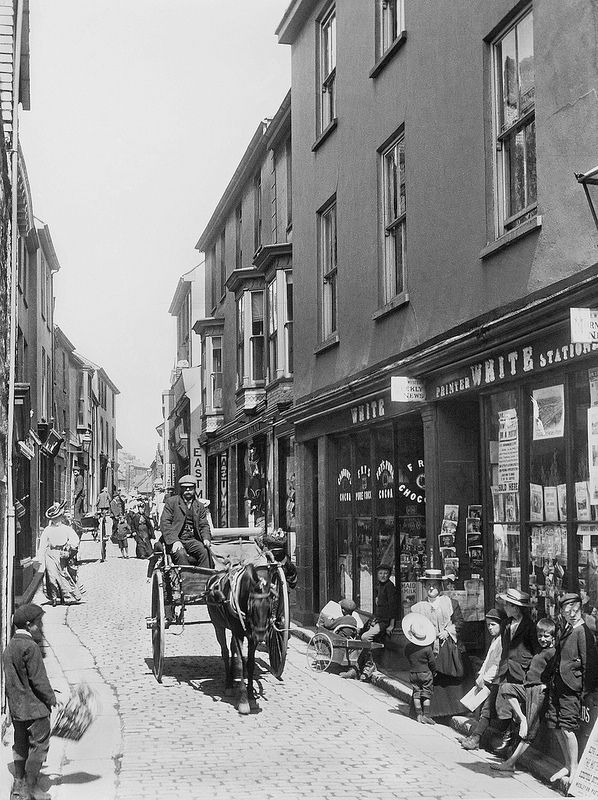 an old black and white photo of a horse drawn carriage in the middle of town