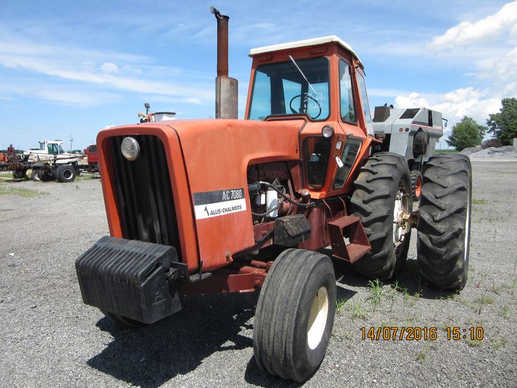 an orange tractor parked on top of a gravel field