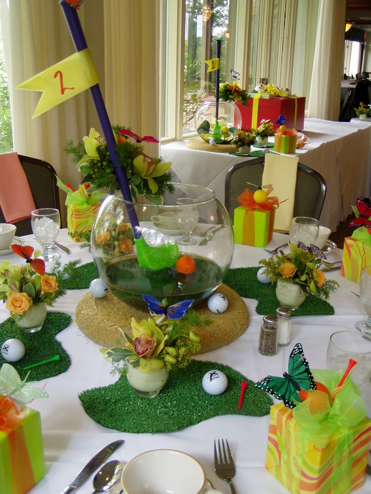 the table is set for a golf themed party with gifts and decorations on it, including a fish bowl