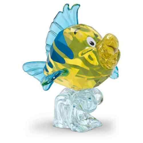 a glass figurine of a yellow fish holding a piece of food in it's mouth