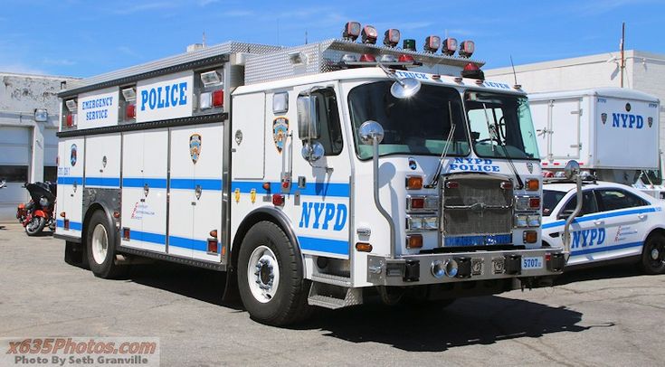 a police truck parked in front of a building next to a white car and another vehicle