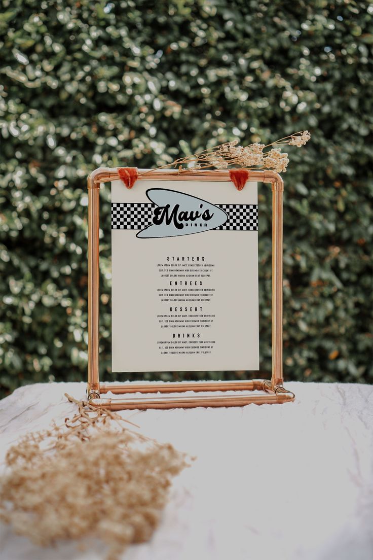 a menu sitting on top of a table next to a plant filled with flowers and leaves