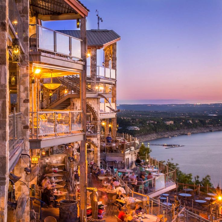 an outdoor restaurant overlooking the water at dusk