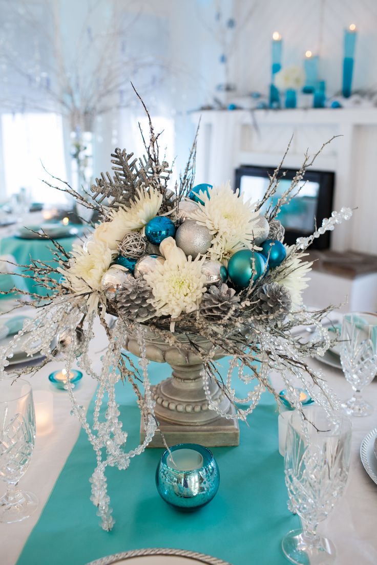 a vase filled with white flowers and blue ornaments on top of a dining room table