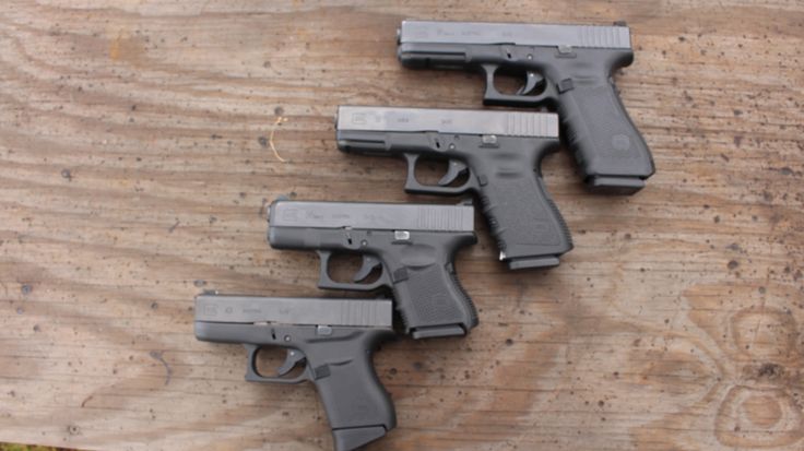 four handguns are lined up on a wooden surface