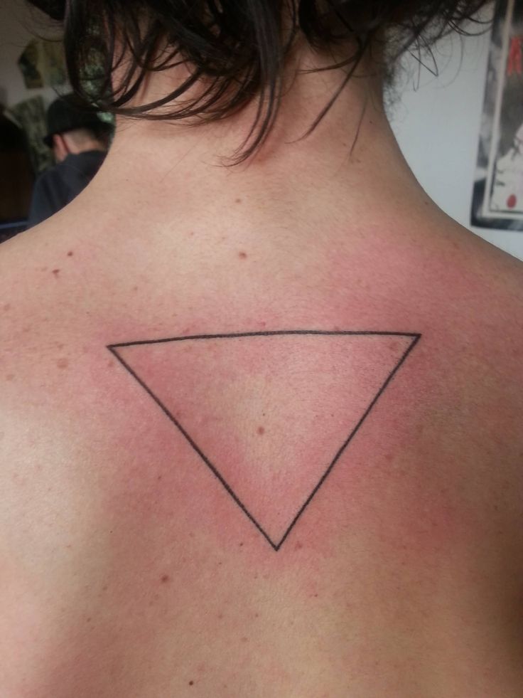 the back of a woman's shoulder with a triangle tattoo on her left side