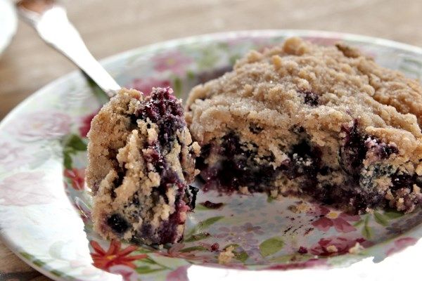 a piece of blueberry crumb cake on a floral plate with a bite taken out