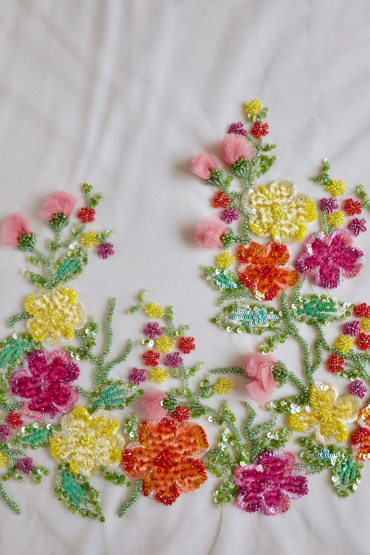 an embroidery pattern with flowers and leaves on white fabric, next to a measuring ruler