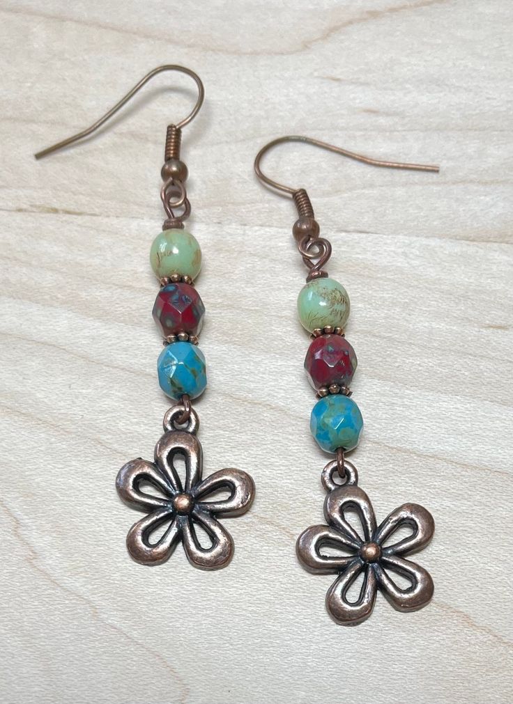 Boho style earrings with rustic vibes!  These were created using Czech Picasso glass beads in sage, sky blue, and dark maroon red.  I have also used copper spacer beads, and antique copper flower charms.  Great casual, everyday earrings! Total length of earrings, including the ear wire, is slightly over 2-1/4".   Matching necklace: https://www.etsy.com/listing/1601876489/rustic-beaded-czech-glass-necklace-with?click_key=a3e58bfd6a6adb1fee441eac4debfa990bed2937%3A1601876489&click_sum=6da8d6b9&ref=shop_home_active_1&frs=1 Matching bracelet: https://www.etsy.com/listing/1587641712/rustic-handmade-beaded-boho-bracelet?click_key=87b993c1a0be3c27bded97932f9f89f3cd6d558c%3A1587641712&click_sum=79f10a43&ref=shop_home_active_1&frs=1 Thank you for shopping with The Lucie Collection! Bohemian Flower Earrings, Bohemian Dangle Flower Earrings Nickel Free, Bohemian Flower Earrings Nickel Free, Handmade Bohemian Flower Earrings, Bohemian Metal Flower Earrings With Ear Wire, Adjustable Bohemian Flower Earrings, Bohemian Style Flower Earrings As A Gift, Bohemian Beaded Earrings With Flower Charm, Bohemian Adjustable Flower Earrings As Gift