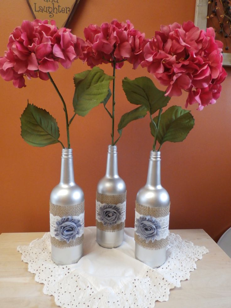 three bottles with flowers in them sitting on a table