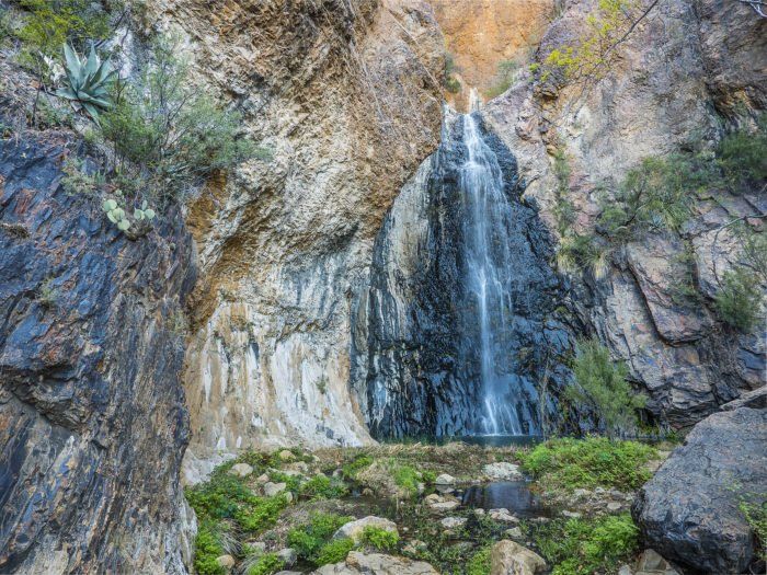 there is a waterfall in the middle of some rocks and plants on the side of it