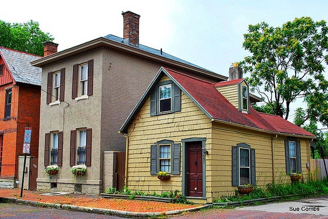 an old yellow house with red roof and windows