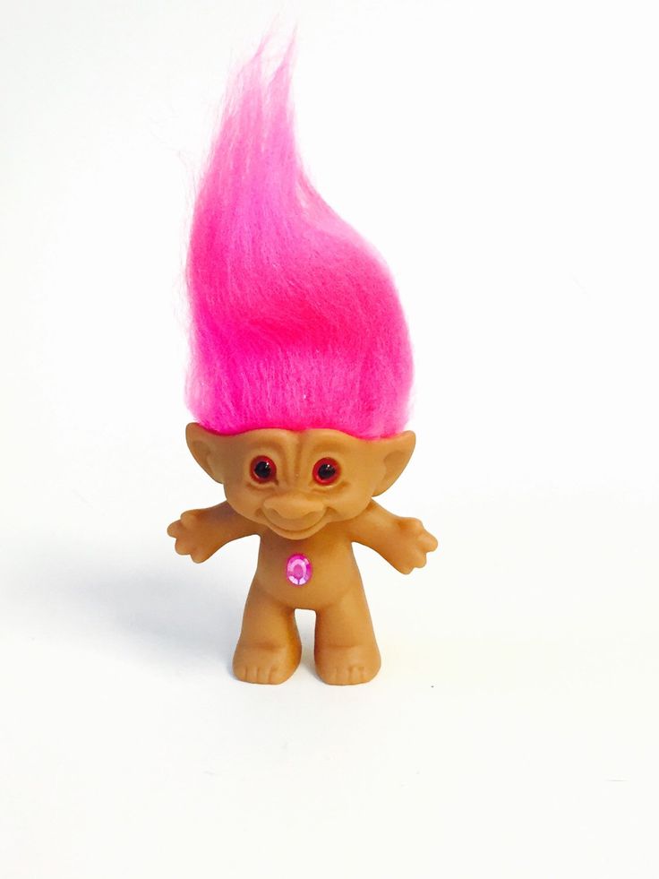 a small toy troll with pink hair on it's head and eyes, standing in front of a white background