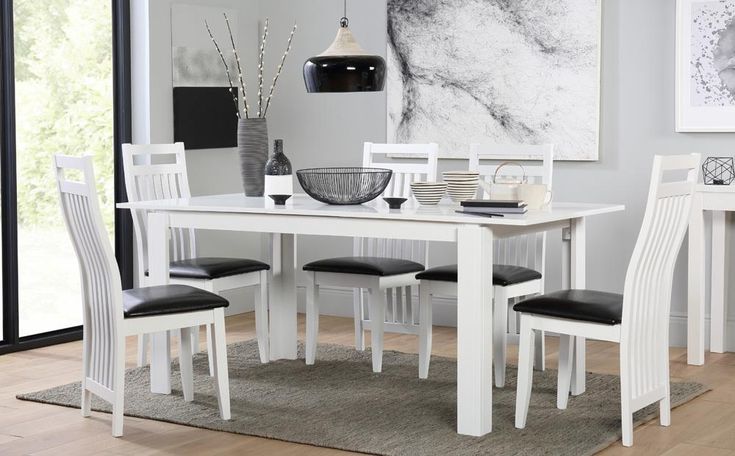 a white dining table with four chairs and a bowl on the table in front of it