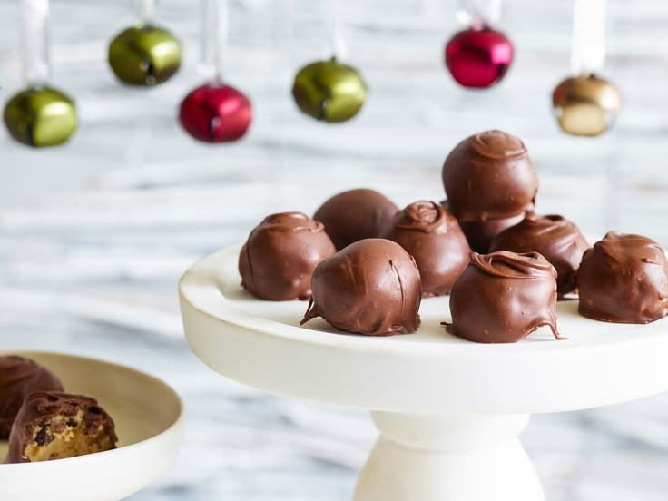 some chocolates are on a white plate with ornaments hanging from the ceiling in the background