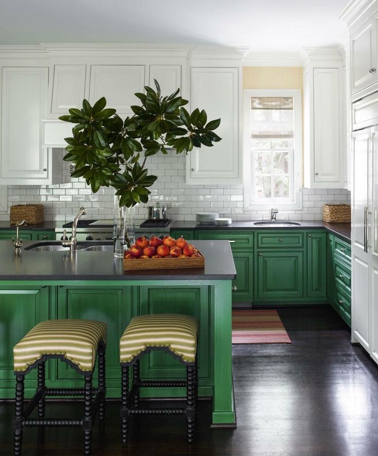 a kitchen with green cabinets and stools in front of the counter top, along with a potted plant on the island