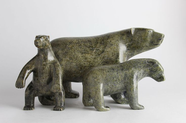 two ceramic bears standing next to each other on a white surface with one bear holding the other's paw