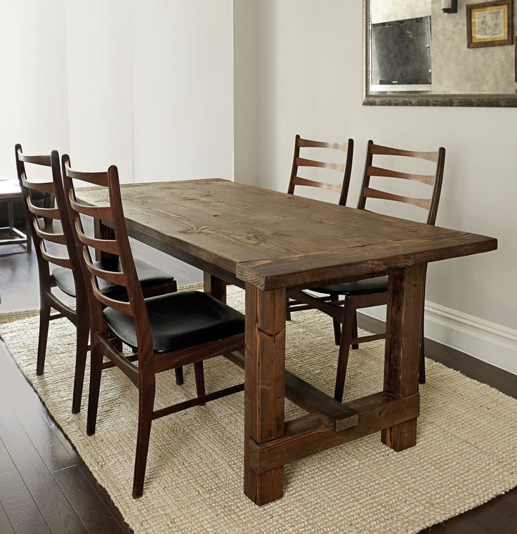 a wooden table with chairs around it and a rug on the floor next to it