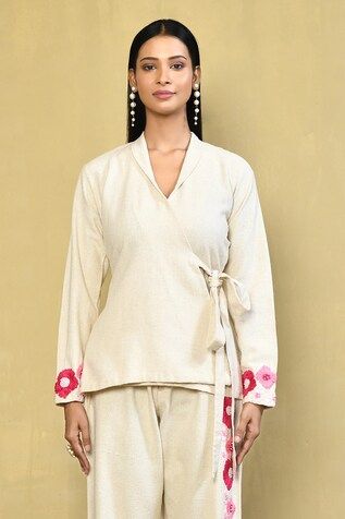 Cream top with a side tie-up and floral embroidered sleeves. Paired with a matching pant with floral embroidery. - Aza Fashions Fitted Embroidered Pant Set For Spring, Spring Embroidered Fitted Pant Set, Spring Floral Embroidered Long Sleeve Pant Set, Spring Floral Embroidery Long Sleeve Pant Set, Spring Cotton Sets With Embroidered Sleeves, Fitted Traditional Pant Set For Spring, Fitted Pant Set With Set-in Sleeves For Spring, Embroidered Loungewear Sets For Spring, Spring Embroidered Loungewear Sets