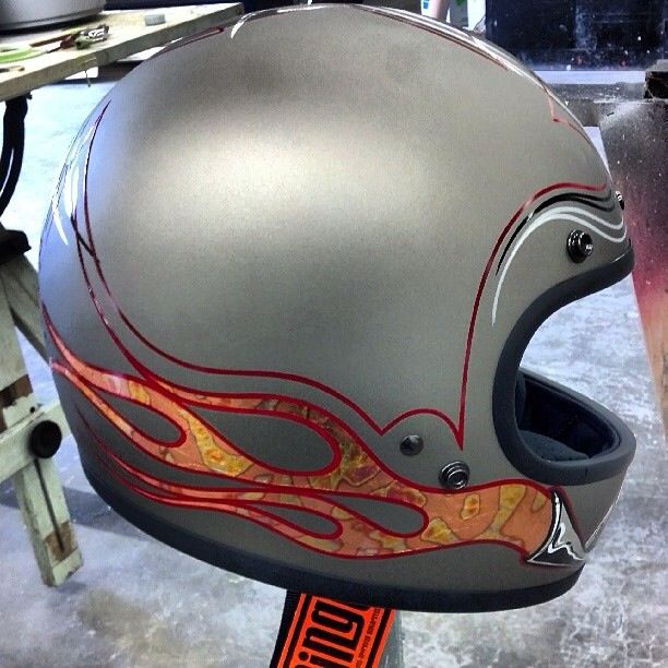 a motorcycle helmet with flames painted on it's face and visor sitting on a stand