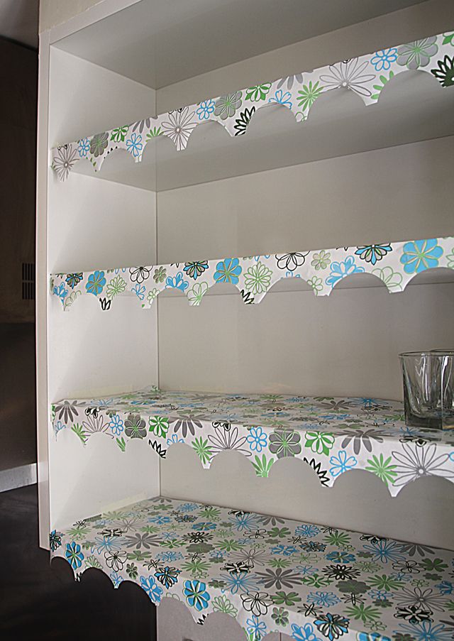 the shelves in the kitchen are decorated with blue and green flowers on them, along with glassware