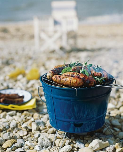 a blue bucket filled with food sitting on top of a rocky beach