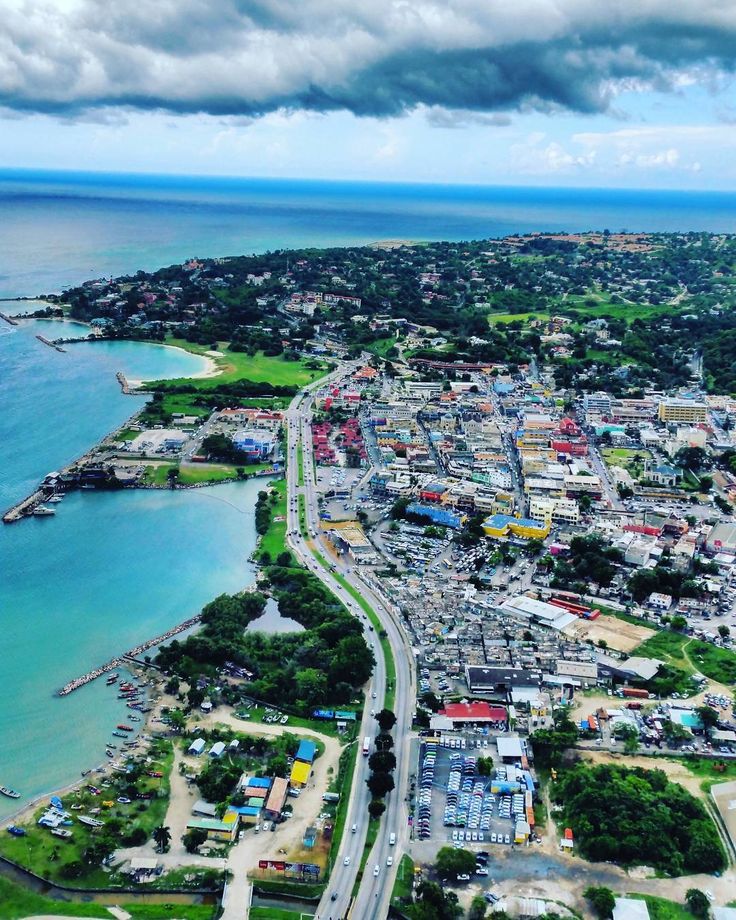 an aerial view of a city by the ocean with lots of buildings and roads on both sides