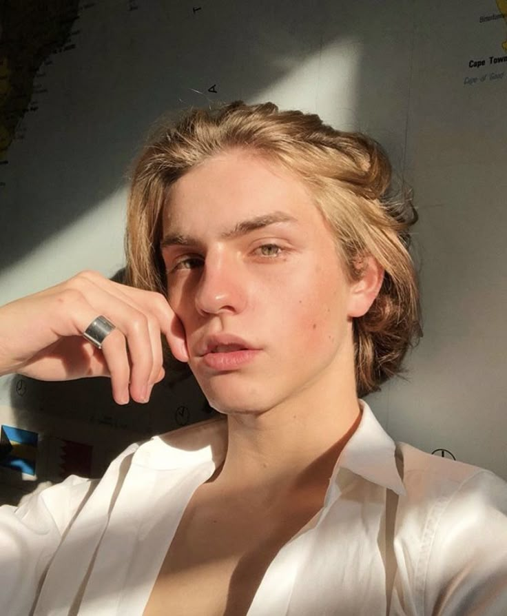 a young man is posing for the camera with his hand on his chin and wearing a white shirt