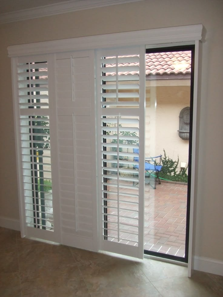 an open window with white shutters in a room that has tile flooring and walls