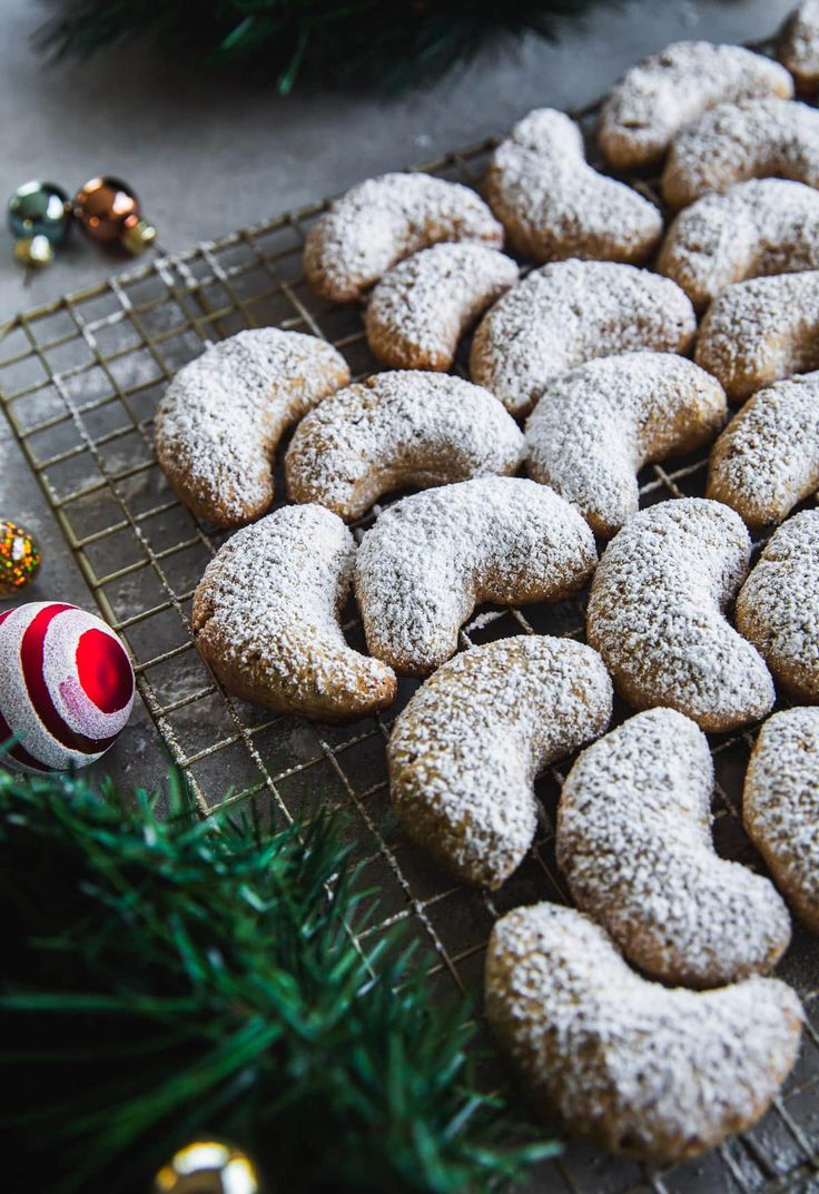 a bunch of cookies that are on a cooling rack next to some christmas decorations and baubles