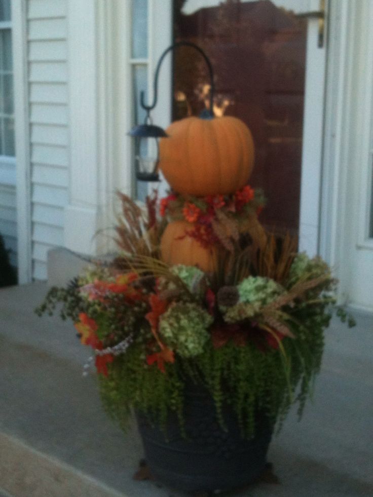 a potted planter with a pumpkin sitting on it's front porch next to a door