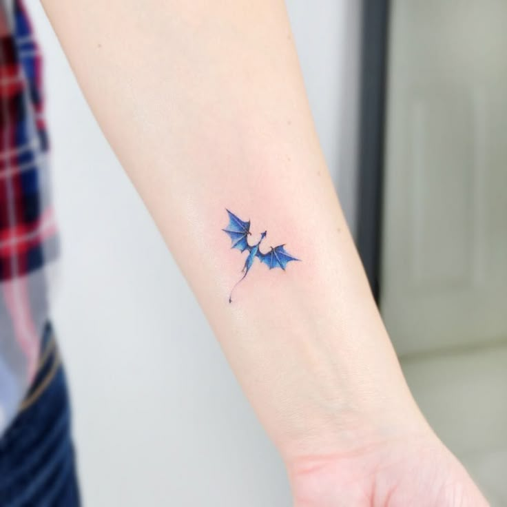 a small tattoo on the wrist of a woman's left arm, with two blue bats