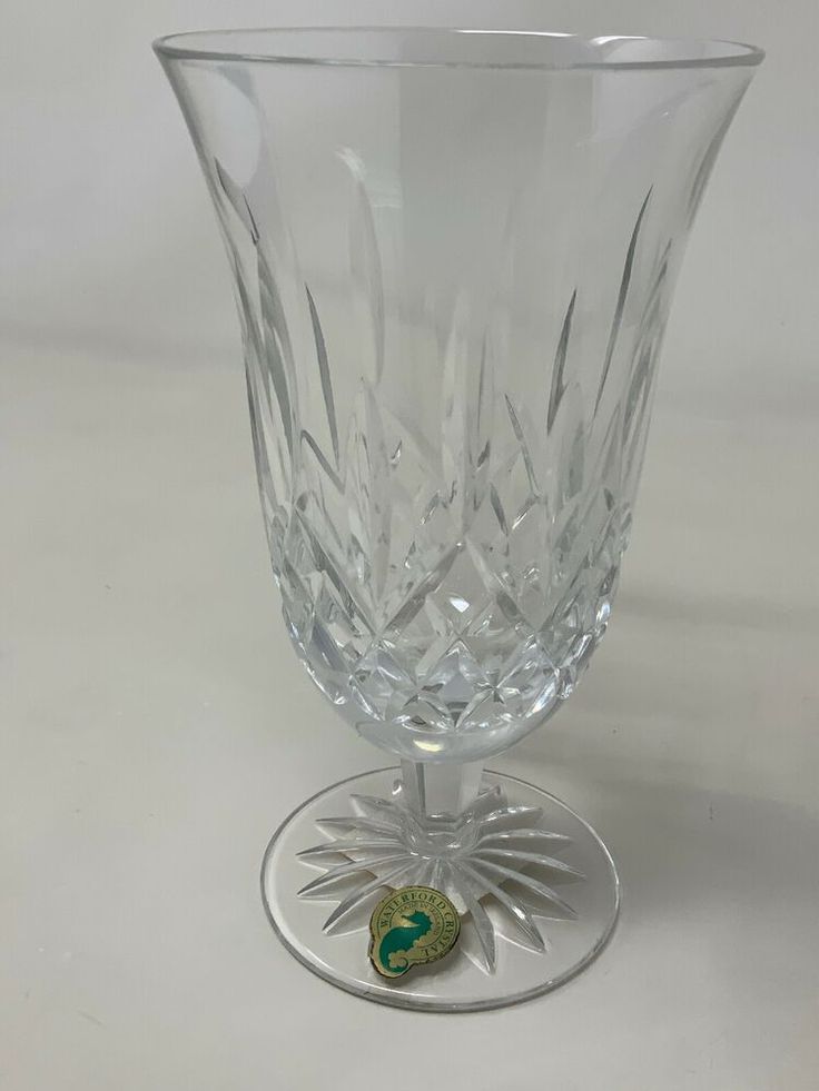 a clear glass vase sitting on top of a white tablecloth covered flooring with a green and gold emblem