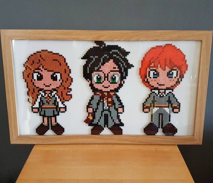 three cross stitch dolls in a wooden frame