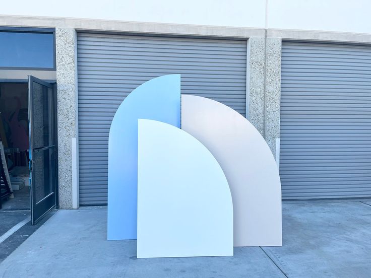 two large white and blue sculptures sitting in front of a garage door with roller doors behind them