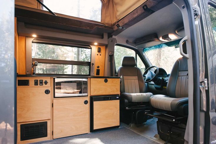 the interior of an rv with wood paneling and leather seats, windows, and cabinets