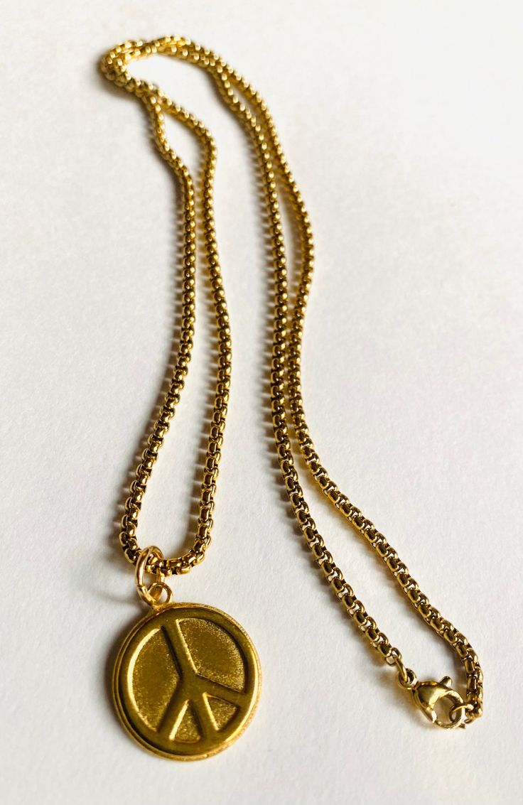 Long Peace Necklace Plated brass. Sturdy coin size charm of brass. Peace sign design. Sturdy long 22" gold over steel chain. Steel lobster clasp. Super fun to wear and layer with other necklaces. Long Peace Necklace Spiritual Gold Long Necklace With Round Beads, Spiritual Style Long Nickel-free Necklace, Spiritual Peace Sign Necklace As A Gift, Peace Sign Design, Adjustable Peace Sign Necklace, Necklaces Long, Peace Necklace, Store Image, Necklace Layering