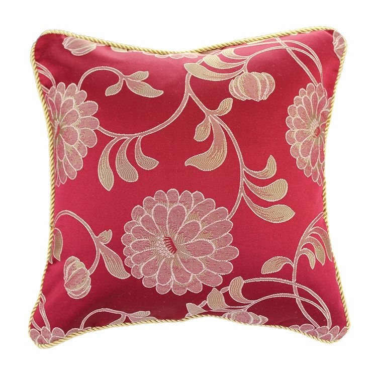 a red pillow with gold trimmings and pink flowers on it's side