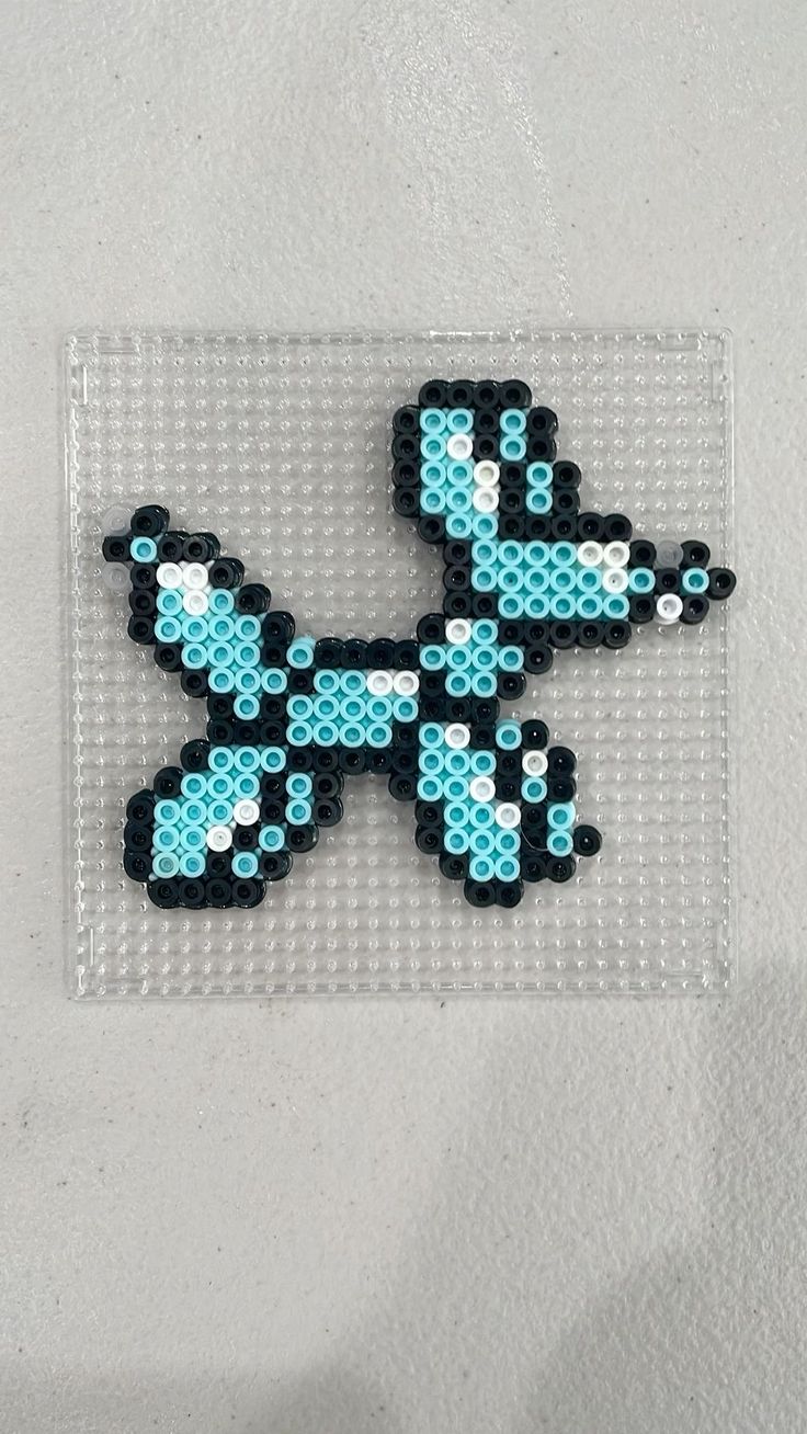 a small pixel art piece is displayed on a white surface with blue and black dots