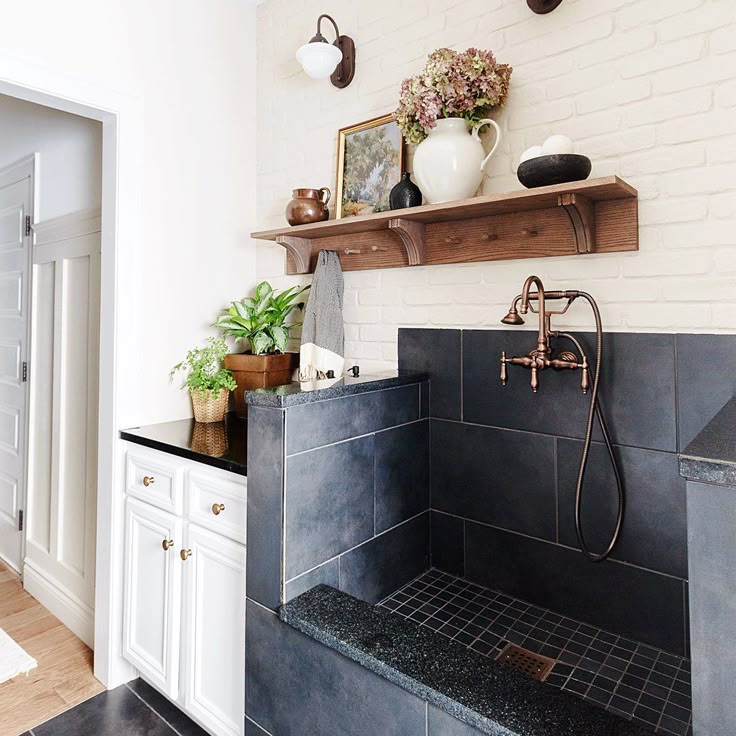 a bathroom with black and white tile, wooden shelves and potted plants on the wall