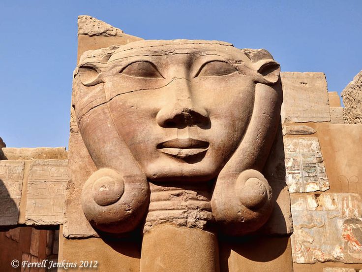 the head of an ancient egyptian statue is shown in front of some ruins and blue sky